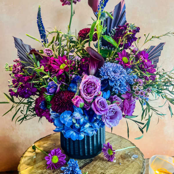 Purple and blue floral arrangement in a dark vase