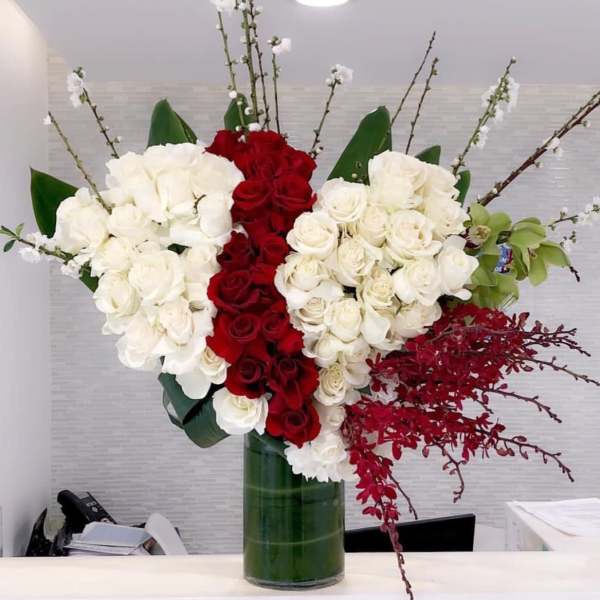 Tall arrangement of red and white roses in a glass vase