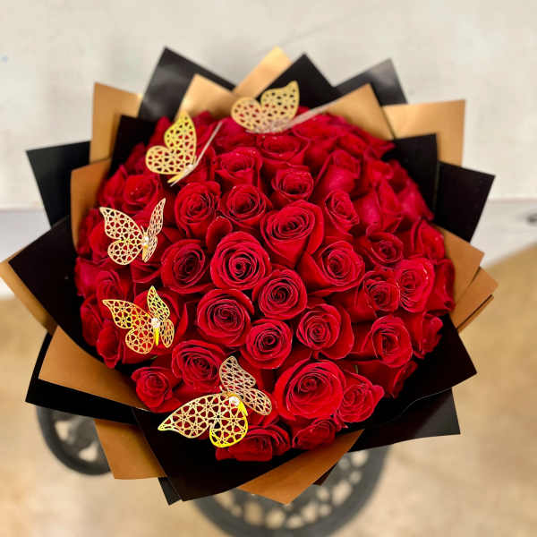 Bouquet of red roses wrapped in black and gold paper with butterfly accents