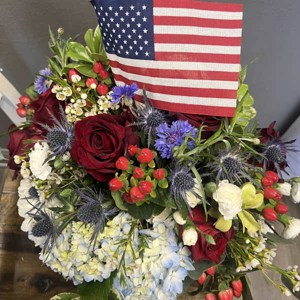 Red roses and blue hydrangeas arranged with an American flag