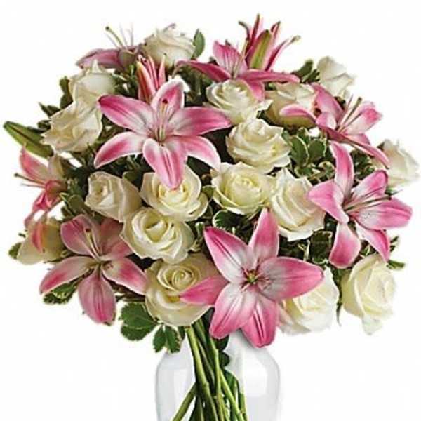 Pink lilies and white roses arranged in a clear glass vase