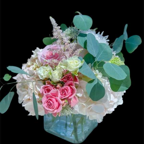 Pink and white roses in a blue glass vase with eucalyptus