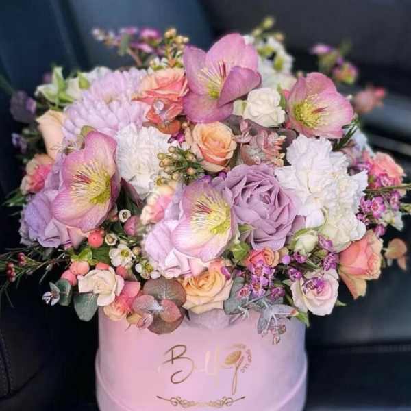 Pink and lavender flower arrangement in a round hat box