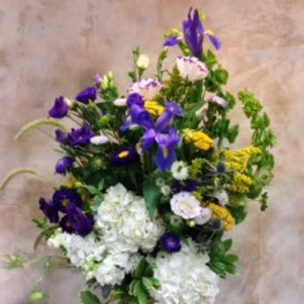 Tall bouquet of purple, white, and yellow flowers in a vase