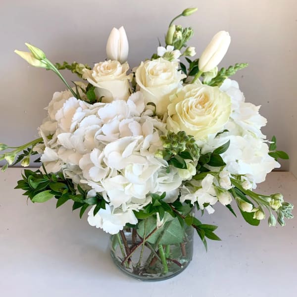 White roses and hydrangeas in a clear glass vase