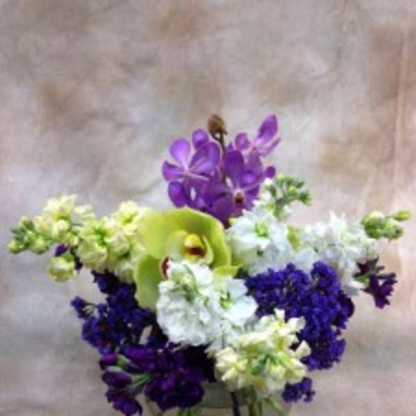 Purple and white floral arrangement in a glass vase