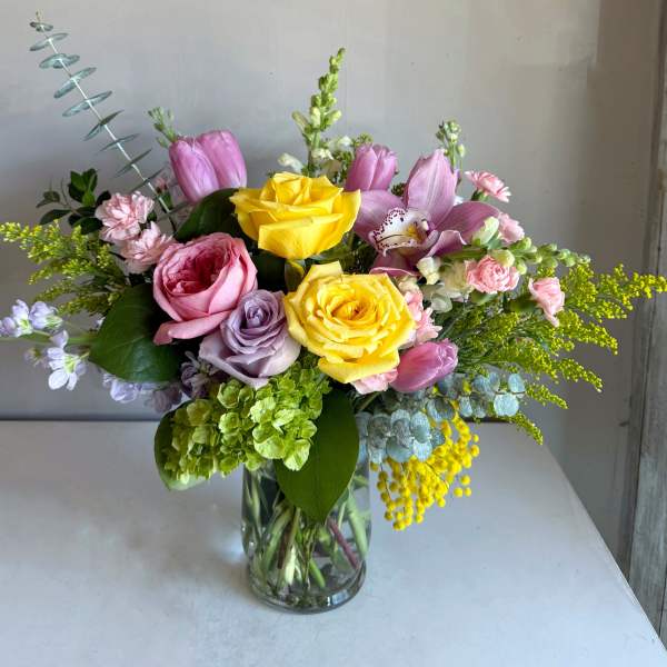 Mixed bouquet of pink and yellow flowers in a clear glass vase