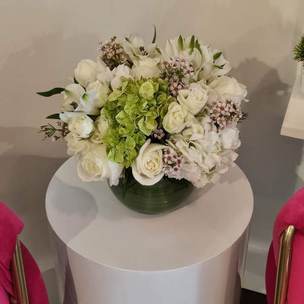 White floral arrangement with green hydrangea in a dark vase