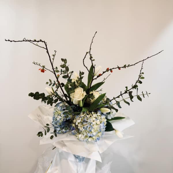 Bouquet of white roses, blue hydrangeas, and white tulips with branching stems