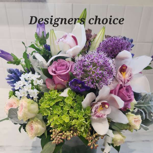 Mixed bouquet with orchids, roses, and purple allium in a dark vase