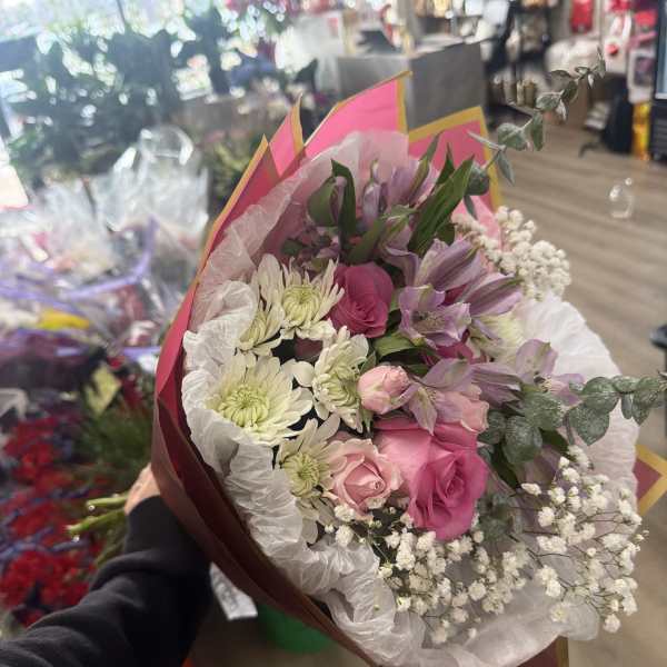 Hand-tied bouquet of pink roses, purple alstroemeria, white chrysanthemums and baby's breath in pink wrap