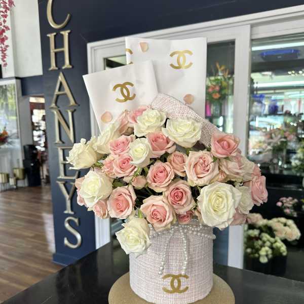 Pink and white roses arranged in a decorated hatbox with pearl accents