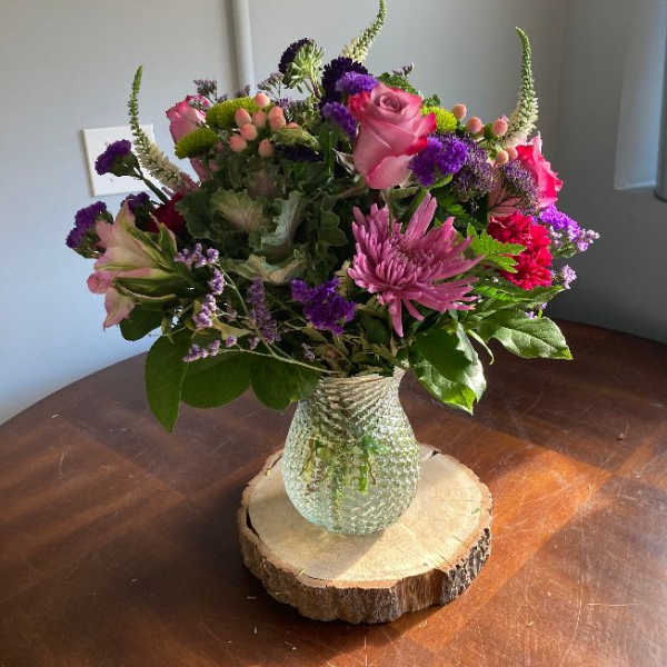 Mixed pink and purple flower arrangement in a glass vase