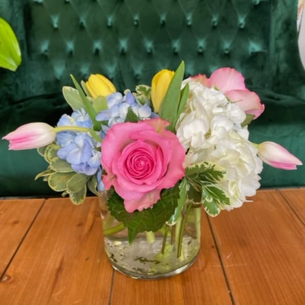 Mixed bouquet in a clear glass vase with pink roses, hydrangeas, and tulips