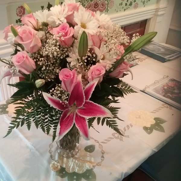 Pink roses and lilies arranged in a clear glass vase