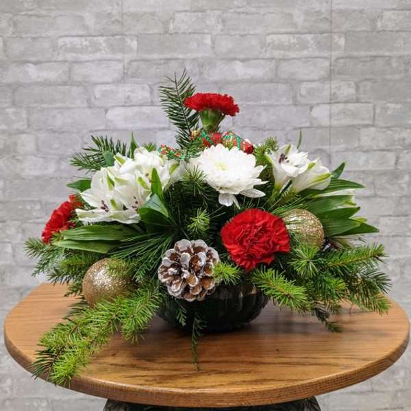 Holiday centerpiece with red carnations, white lilies, pinecones, and evergreen branches