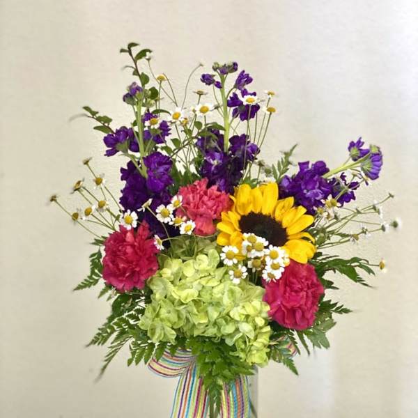 Colorful mixed bouquet in a clear glass vase with a striped ribbon