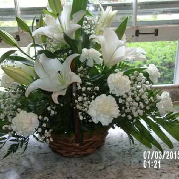 White lilies and carnations in a wicker basket arrangement