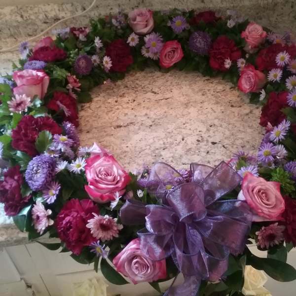 Heart-shaped floral wreath with pink roses and purple flowers