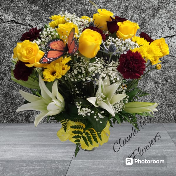 Bouquet of yellow roses, white lilies, and burgundy flowers in a vase