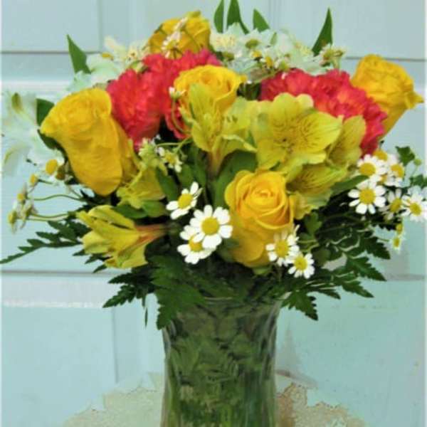 Bouquet of yellow and red flowers in a clear glass vase