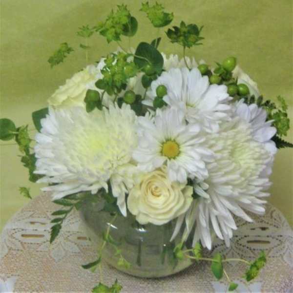 White daisies and roses arranged in a glass vase