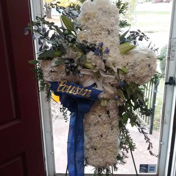 White funeral standing spray with lilies and blue ribbon on an easel