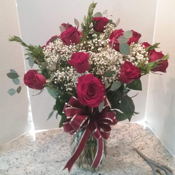 Bouquet of red roses with baby's breath in a glass vase