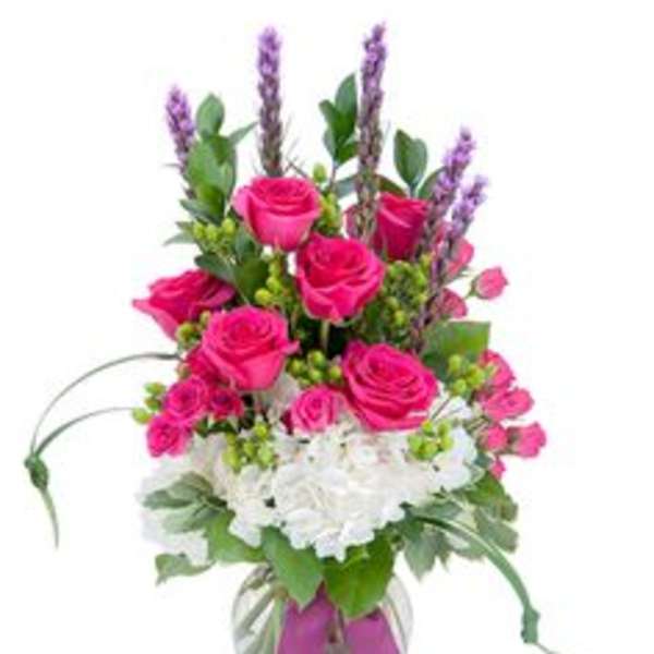 Pink roses and white hydrangeas in a glass vase with a ribbon