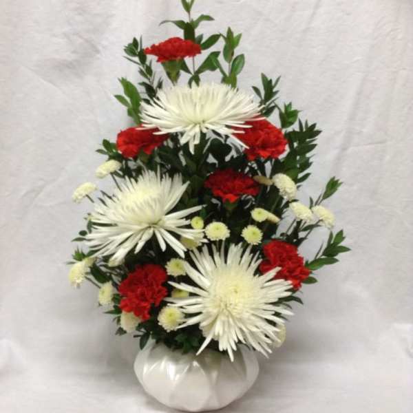 White spider mums and red carnations in a white vase