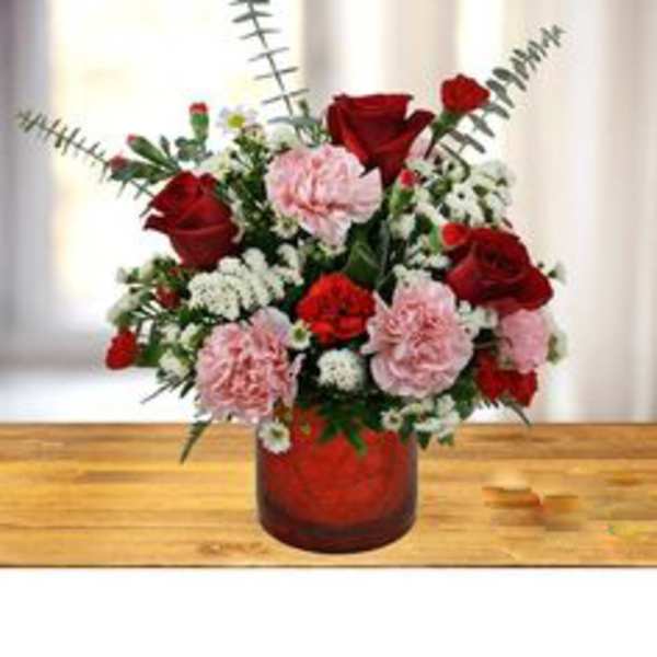 Red roses and pink carnations in a red glass vase