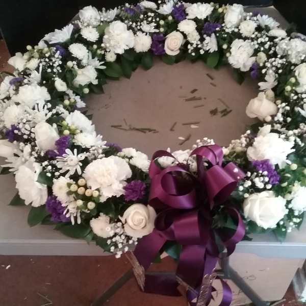 White and purple floral wreath with a large purple ribbon bow