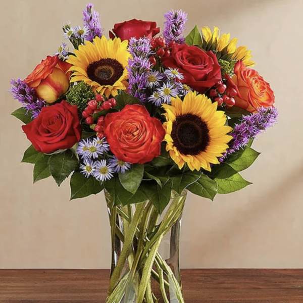 Bouquet of red roses and sunflowers in a clear glass vase