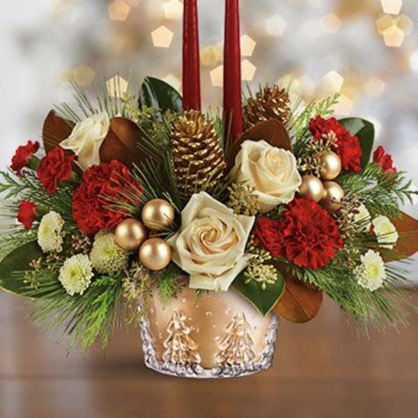 Holiday centerpiece with red candles, white roses, and pinecones in a gold vase