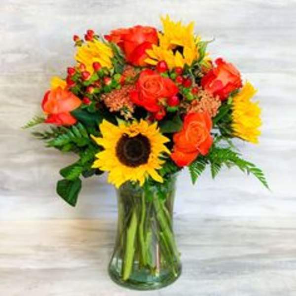 Bouquet of sunflowers and orange roses in a glass vase