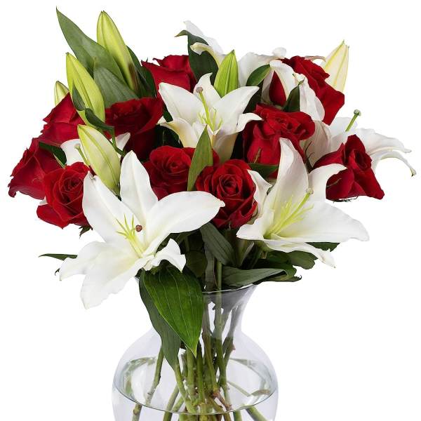 Red roses and white lilies arranged in a clear glass vase with water