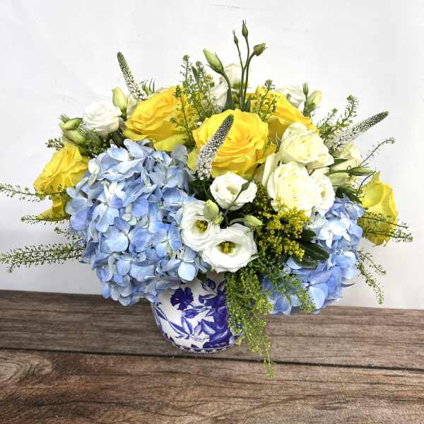 Yellow and white roses with blue hydrangeas in a blue-and-white vase