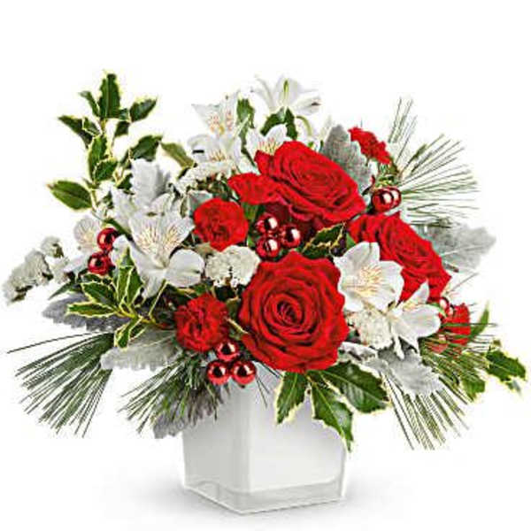 Red roses and white lilies in a white vase with holiday greenery