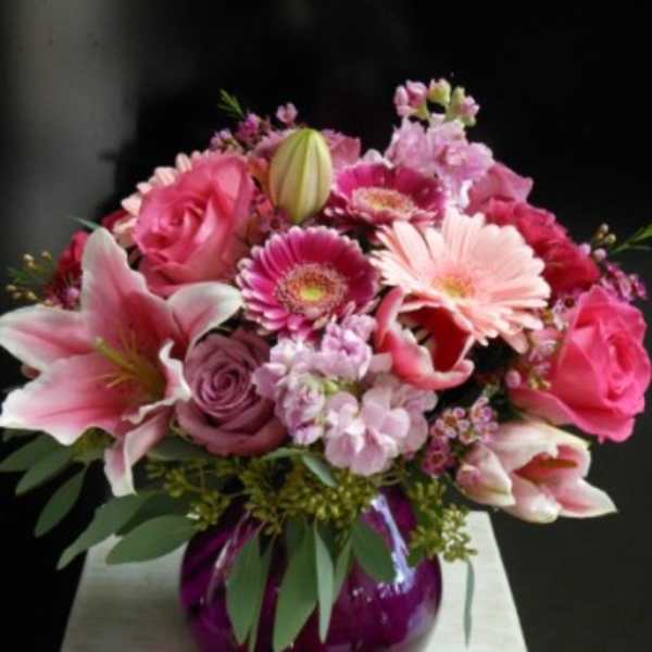 Pink mixed bouquet in a purple glass vase