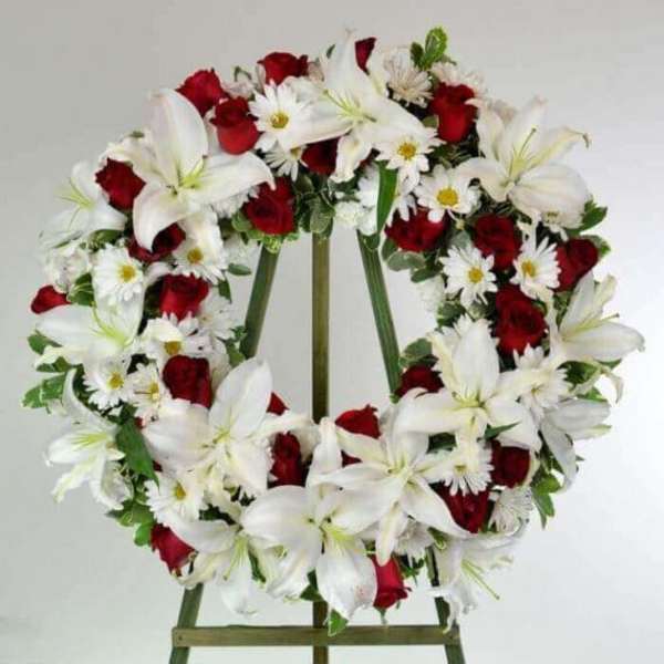 Heart-shaped wreath of red roses and white lilies on an easel