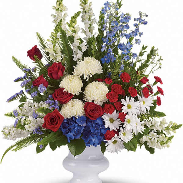 Tall red, white, and blue flower arrangement in a white pedestal vase