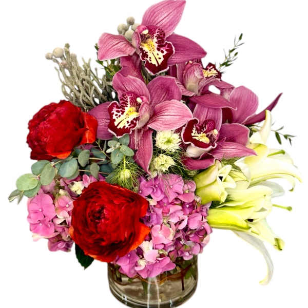 Mixed bouquet in a glass vase with pink orchids, red roses, and lilies