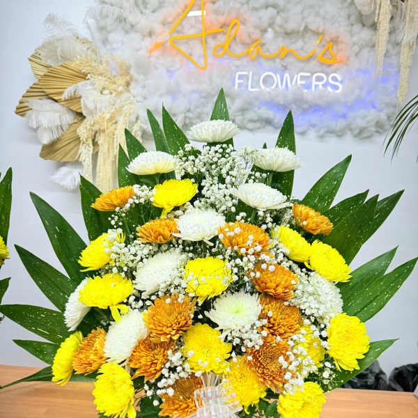 Yellow and white chrysanthemum bouquet in a white vase with ribbon