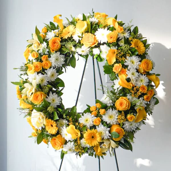 Yellow and white floral wreath on a black stand