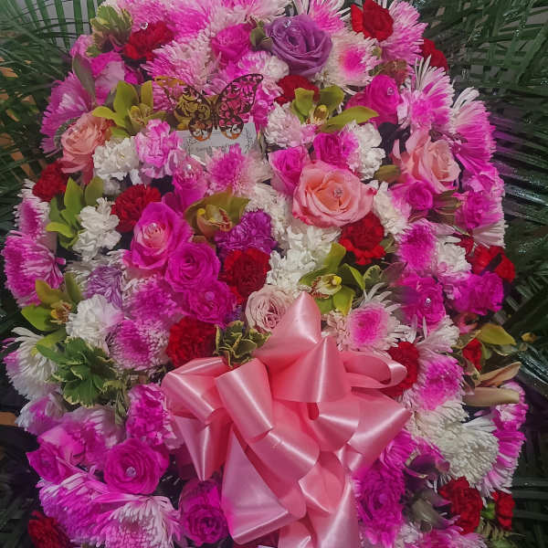 Large pink and white floral standing spray with a satin bow