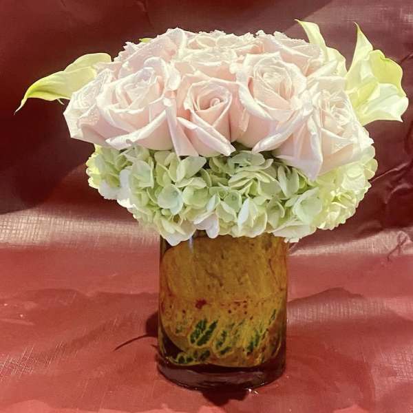 Pink roses and pale hydrangeas arranged in a glass vase.
