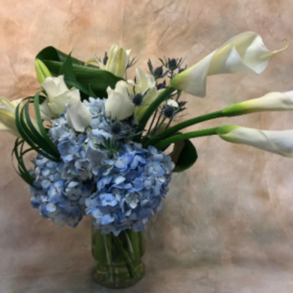 Blue hydrangeas and white calla lilies in a glass vase