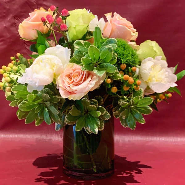 Pink and white roses arranged in a dark glass vase