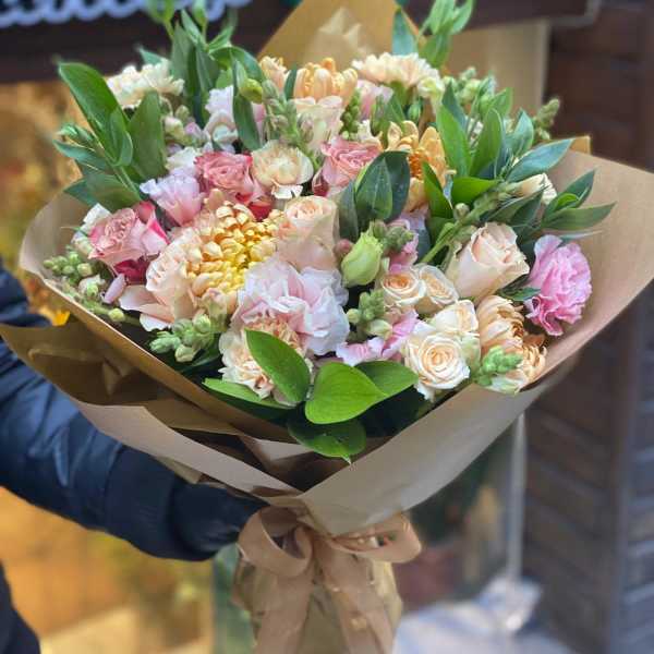 Bouquet of pink and peach flowers wrapped in brown paper