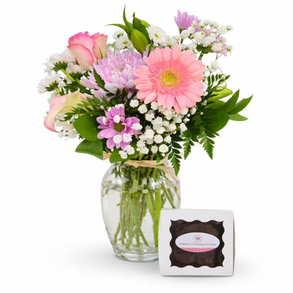 Mixed pink and white bouquet in a glass vase with a box of fudge